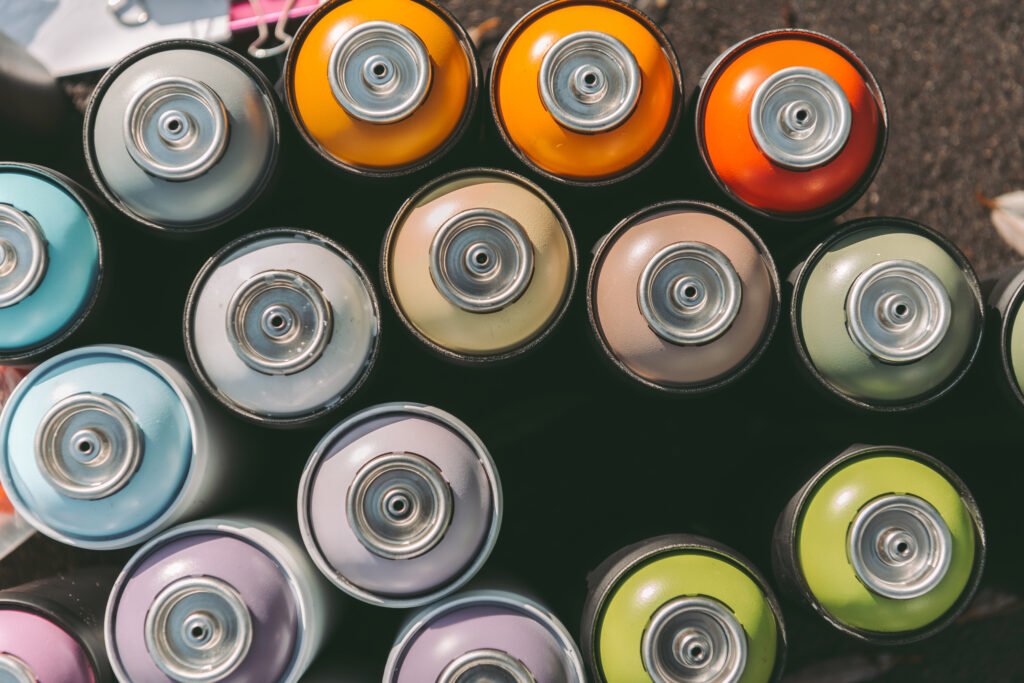 top view of cans with colorful spray paint for graffiti on asphalt